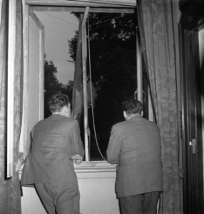 Oranjehaven, de Engelandvaarders club in Londen. Twee mannen kijken uit een ra, Bestanddeelnr 935-2578