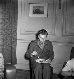 Oranjehaven, de Engelandvaarders club in Londen. Man eet met bord op schoot, Bestanddeelnr 935-2581