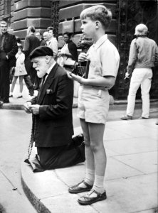 Oude man bidt op straat rozenkrans, (rechts) jongetje met fotoetoestel, Londen, Bestanddeelnr 924-9428