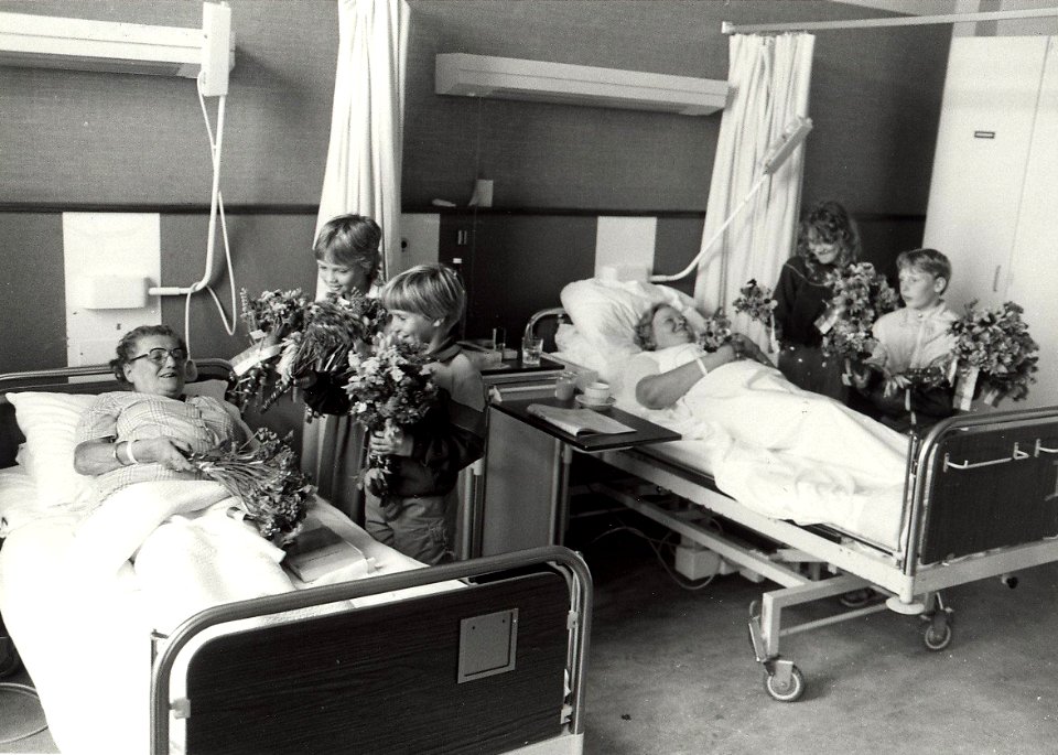 Oude traditie weer in ere hersteld kinderen van de Fuhropschool brengen bloemen van de schooltuin, aan patiënten in de St. Johannes de Deo. NB. links Mw. van Leuven, rechts Mw. van Boxtel. A, NL-HlmNHA 1478 25900 K 38