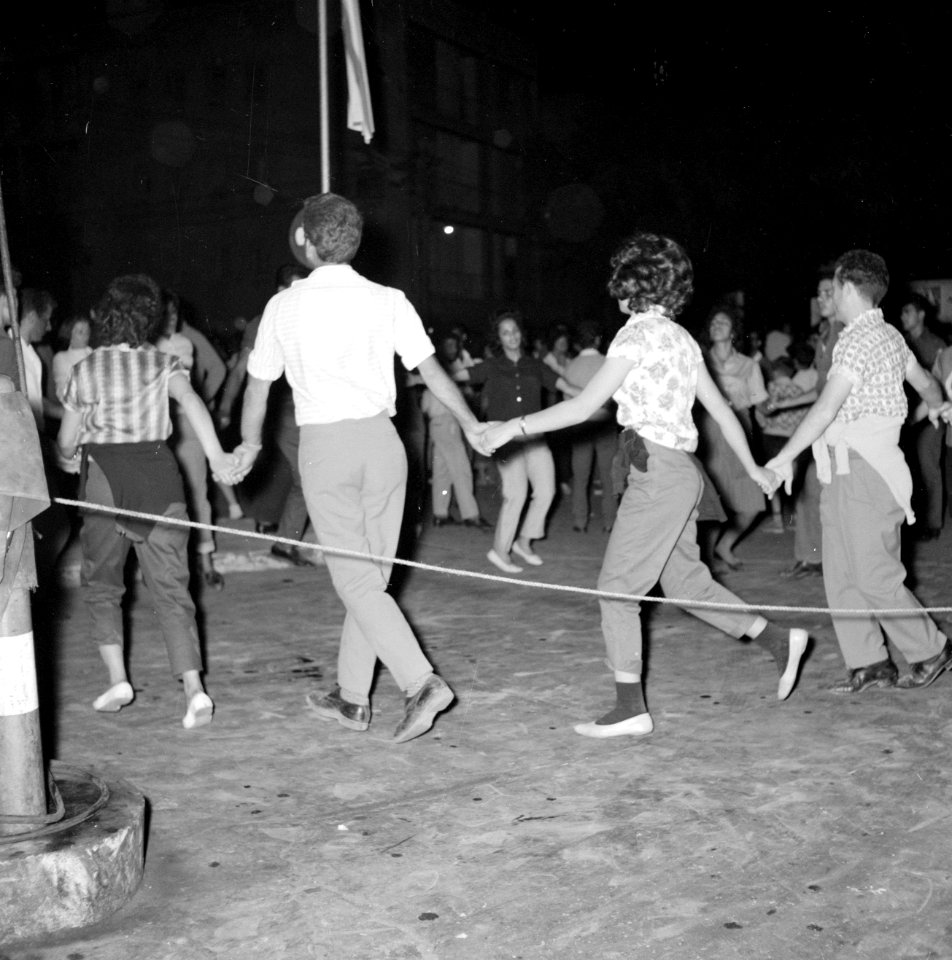 Op straat dansen mensen in een kring terwijl ze elkaars handen vasthouden, Bestanddeelnr 255-1923
