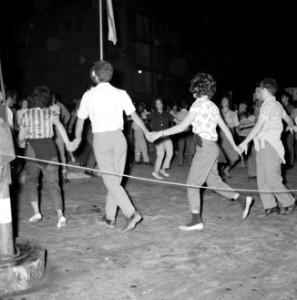 Op straat dansen mensen in een kring terwijl ze elkaars handen vasthouden, Bestanddeelnr 255-1923