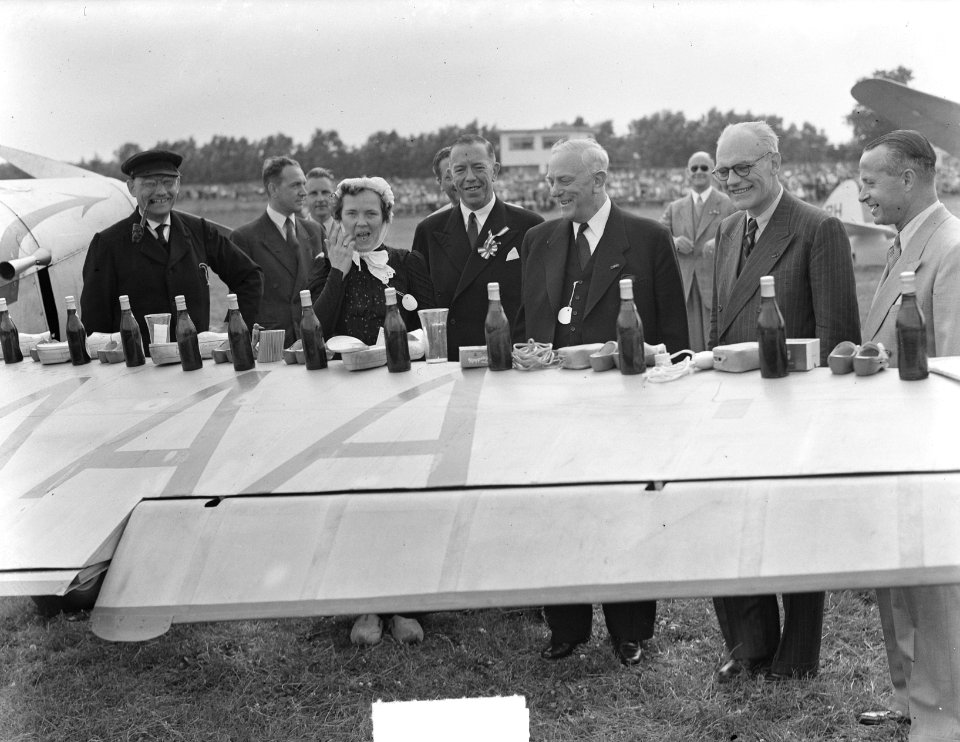 Op viegtuigvleugel zijn souvenirs uitgestald. Mannen en vrouwen in klederdracht, Bestanddeelnr 904-0954