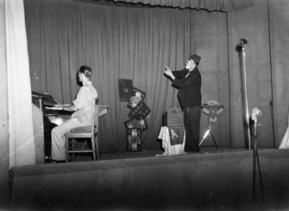 Op toneel een goochelende clown. Hij wordt begeleid door een pianist, Bestanddeelnr 15905