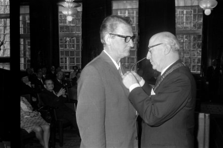 Parool columnist Simon Carmiggelt (links) krijgt onderscheiding opgespeld door b, Bestanddeelnr 923-4797