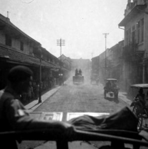 Pantserwagen rijdt door een straat van een stad. Rechts zijn z.g. delman of do…, Bestanddeelnr 15760