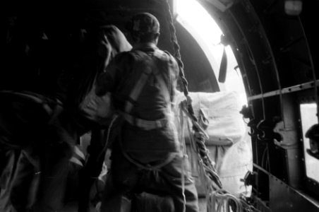 Parachutisten bezig met het droppen van voorraden vanuit de deuropening van een vliegtuig, Bestanddeelnr 2710