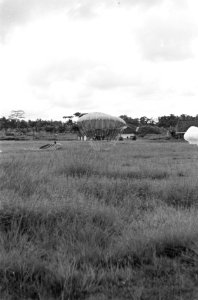 Parachutes met lading komen neer in een veld, Bestanddeelnr 5810
