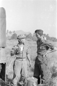 Parachutist drinkt melk uit een mok en praat met een andere militair, Bestanddeelnr 247-4-4