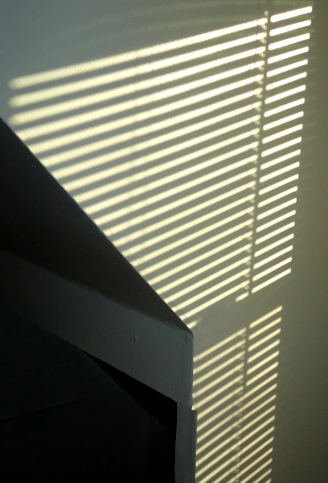Pattern of light on a white wall made by sun through blinds