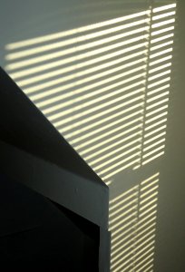 Pattern of light on a white wall made by sun through blinds photo