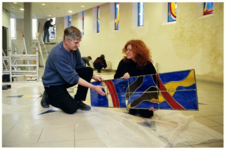 Pastoor Van Oploo en glazenierster Marie-Louise Hebly met een gedeelte van de glas-in-lood-panelen voor het nieuwe Ontmoetingscentrum Regina Caeli in Beverwijk. NL-HlmNHA 54036969