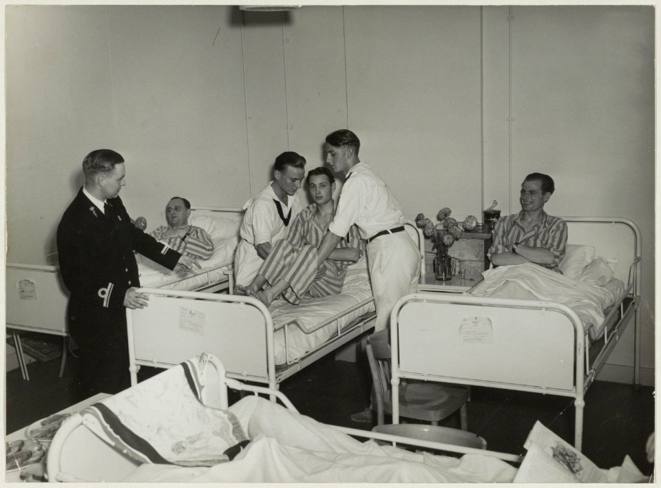Patiënten in het Marine Hospitaal. Twee verplegers krijgen instructies van H.v.d.Velden. NL-HlmNHA 54010272