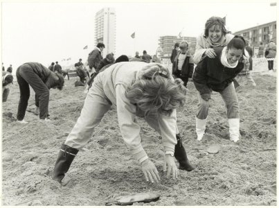 Paaseieren zoeken op het strand. Op de achtergrond de hoge flats op de Zandvoortse boulevard. NL-HlmNHA 54005624
