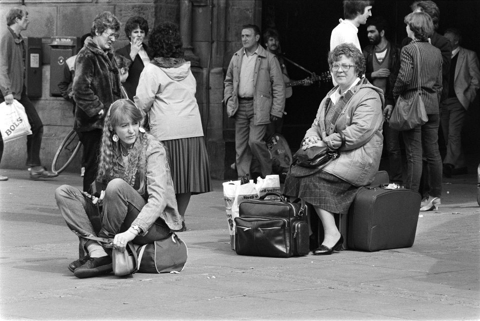 Paasdrukte in Amsterdam meisje en vrouw zittend met bagage voor het CS, Bestanddeelnr 932-9401
