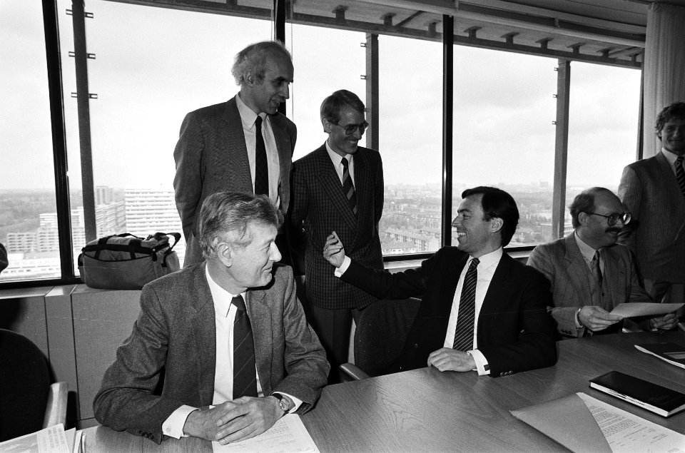 Overleg omroep-CAO zittend de ministers De Koning (l) en Brinkman, staand NOS-v, Bestanddeelnr 933-3124