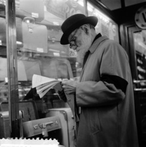 Plaatjes uit Barcelona Oude man met baard leest krant voor een etalage met koff, Bestanddeelnr 908-2773
