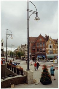 Plaatsing van nieuwe lantaarnpalen op de Grote Houtbrug, gezien vanuit de Grote Houtstraat richting Houtplein. NL-HlmNHA 54036189