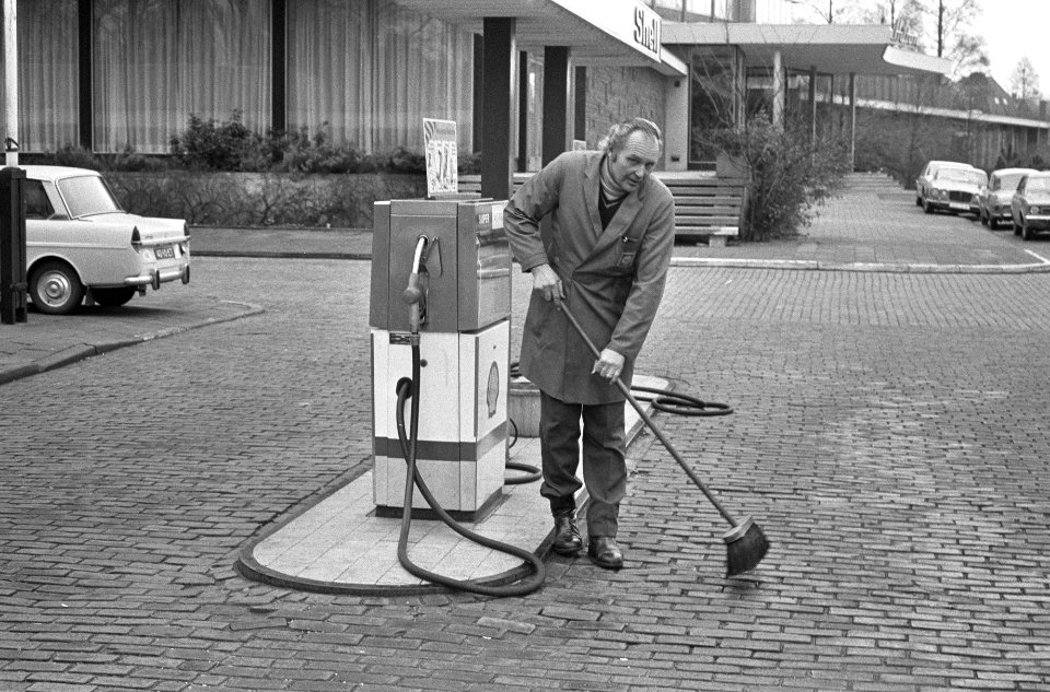 Pompstationbediende veegt het terrein van het benzinestation, Bestanddeelnr 926-9349