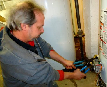 Plumber uses two wrenches to tighten a fitting photo