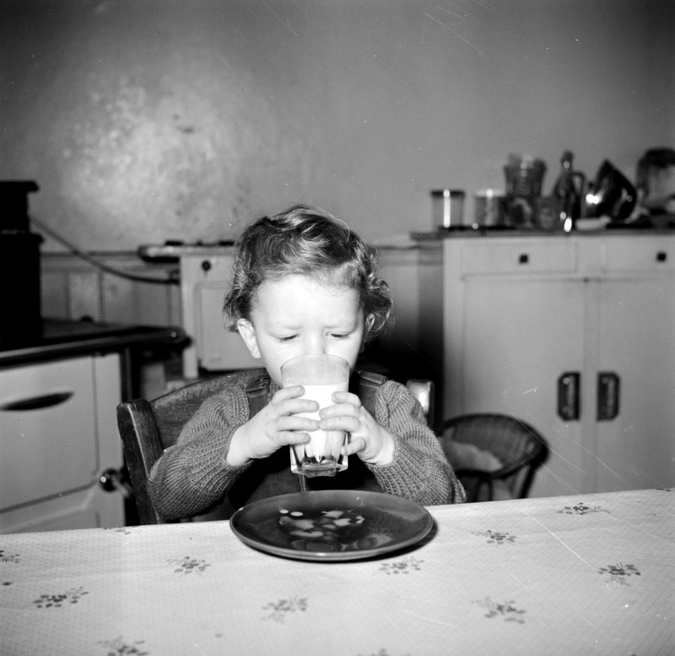 Peuter bij het drinken van een glas melk aan de keukentafel, Bestanddeelnr 252-9384