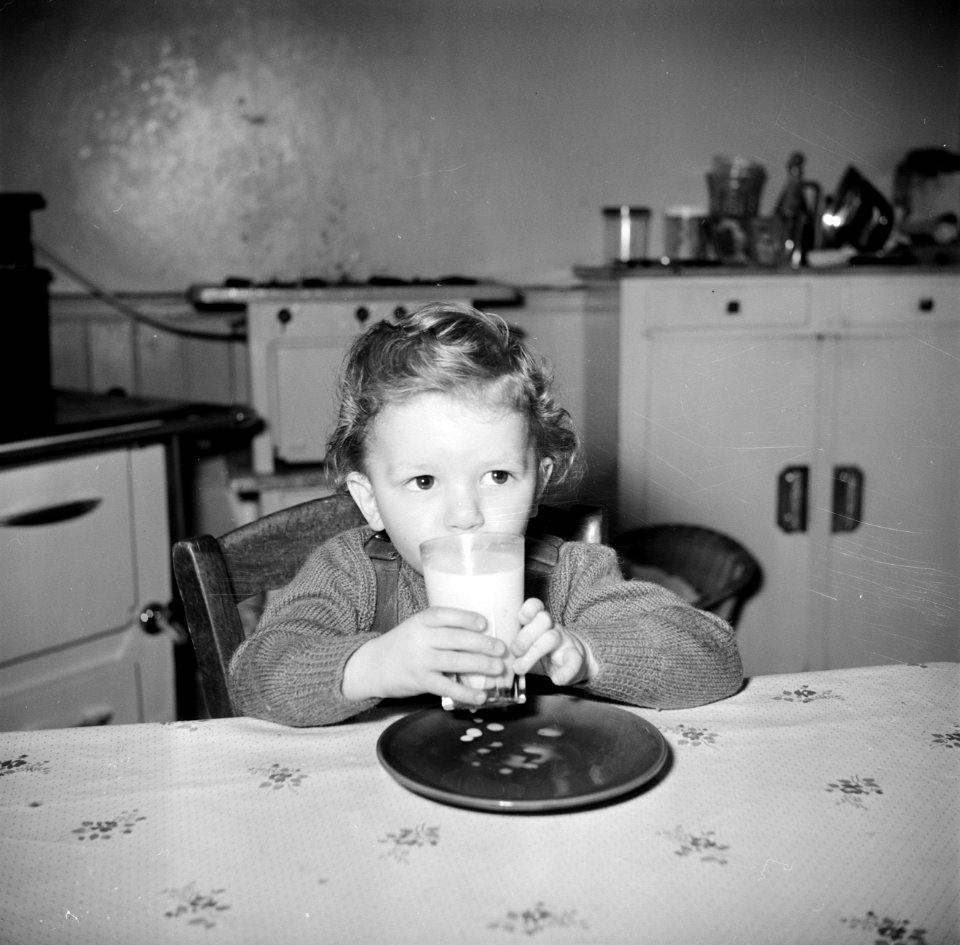 Peuter bij het drinken van een glas melk aan de keukentafel, Bestanddeelnr 252-9385