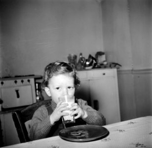 Peuter tijdens het drinken van een glas melk aan de keukentafel, Bestanddeelnr 252-9386