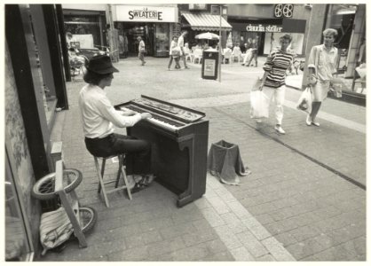 Pianist Beat Rennenmund met zijn scheepspiano uit Zwitserland speelt in de Anegang. NL-HlmNHA 54025533