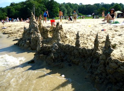 Sandcastle seen from lake with people in background photo