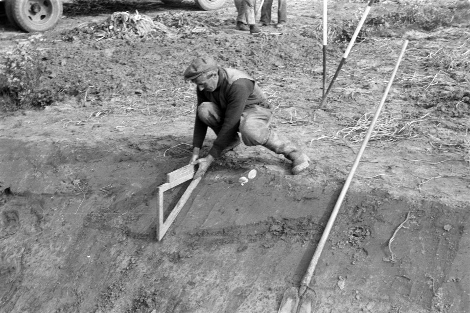 Ruilverkaveling de Vierbannen. Arbeider met waterpas meet hellingshoek te grave…, Bestanddeelnr 170-1197