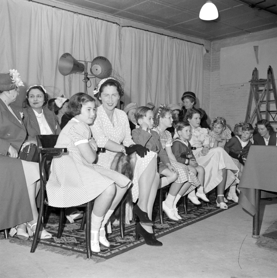 Ruimte met vrouwen en kinderen zittend op houten stoelen, Bestanddeelnr 255-8494
