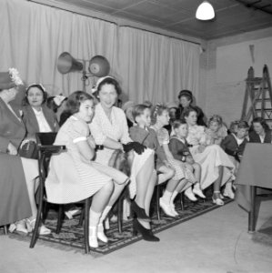 Ruimte met vrouwen en kinderen zittend op houten stoelen, Bestanddeelnr 255-8494