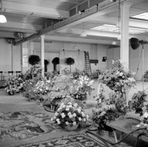 Ruimte met bloemstukken, sierbomen en tapijten (vermoedelijk cadeaus bij recepti, Bestanddeelnr 255-8484