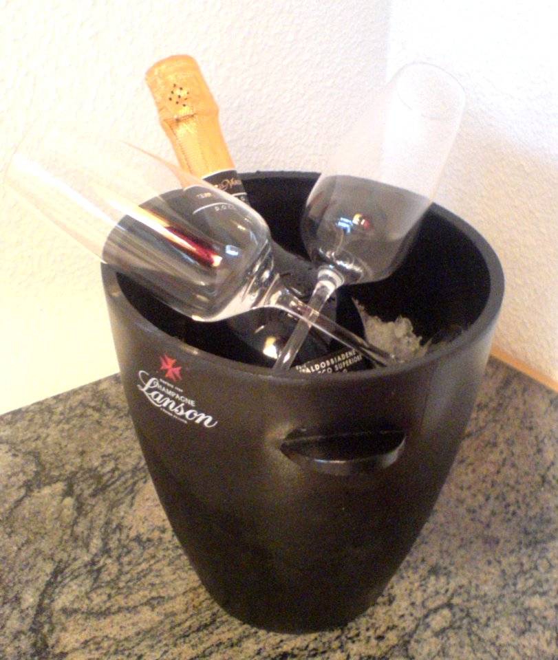 Sektkübel mit Flasche (Prosecco), Eiswürfeln und Gläsern (Lanson)