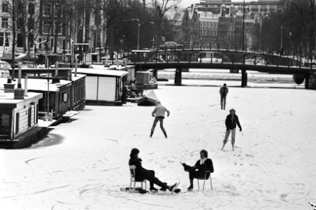 Schaatsen op Nieuwekeizersgracht en twee mensen zittend op stoelen op het ijs, Bestanddeelnr 931-8703