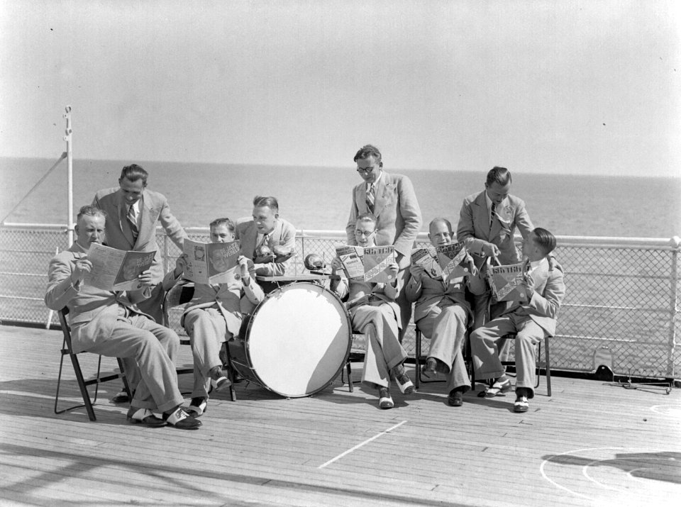 Scheepsorkest aan dek de heren lezen de muziekbladen De Jazzwereld en Rhythm, Bestanddeelnr 189-0538