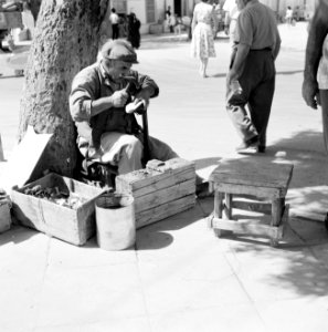 Schoenmaker in de openlucht aan het werk met een schoen die hij op een leest hee, Bestanddeelnr 255-3517 photo