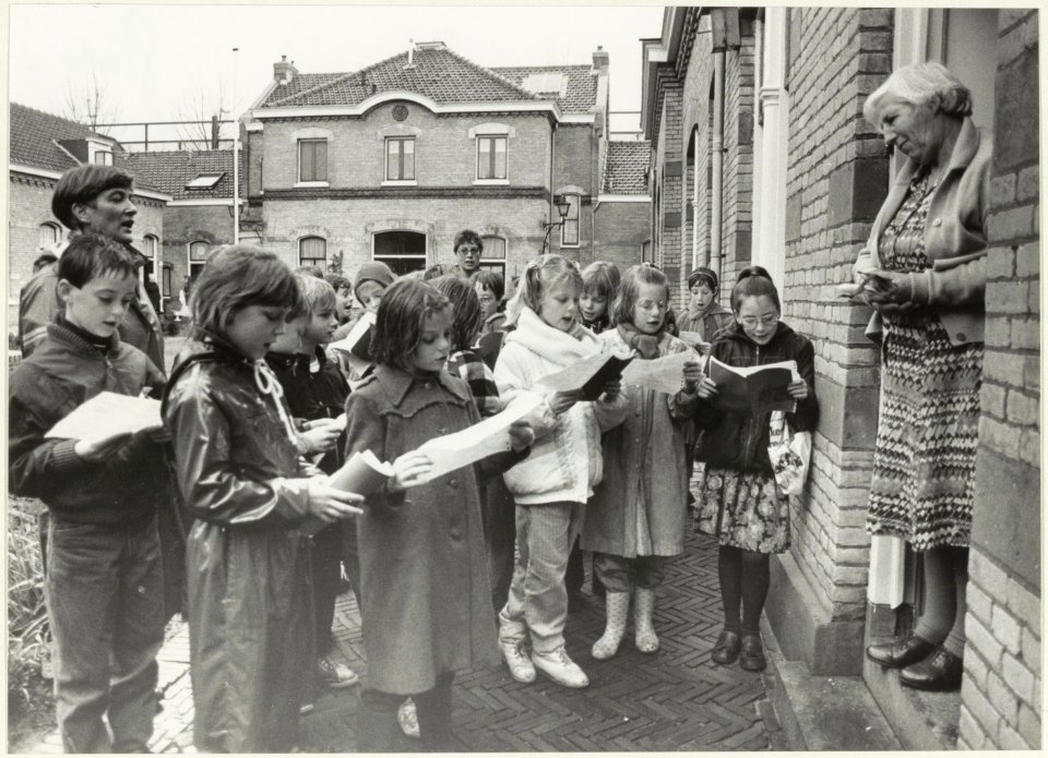 Scholieren van de Dreefschool brengen een kerstgroet aan de bewoonsters van het Zuiderhofje. NL-HlmNHA 54023285