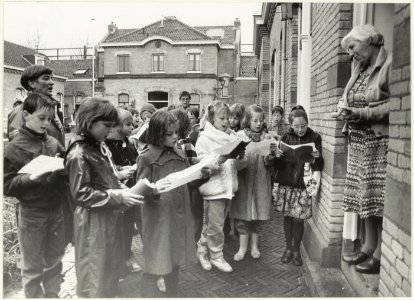 Scholieren van de Dreefschool brengen een kerstgroet aan de bewoonsters van het Zuiderhofje. NL-HlmNHA 54023285