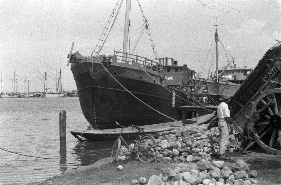 Schip ligt aangemeerd in een haven. Op de voorgrond keien en een kar, Bestanddeelnr 389-6-1