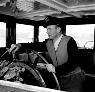 Schipper Anton Rieb aan het roer van de Damco 9, vermoedelijk in West- Duitsland, Bestanddeelnr 254-1353