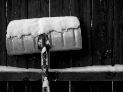 Snow shovel, rear, against wooden fence