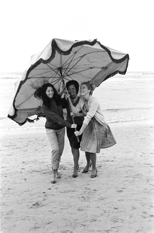 Slecht weer in het weekend. Dames met parasol maken strandwandeling, Bestanddeelnr 915-3397