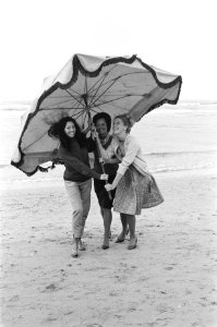 Slecht weer in het weekend. Dames met parasol maken strandwandeling, Bestanddeelnr 915-3397