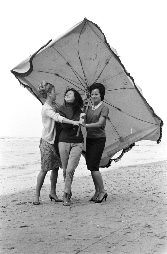 Slecht weer in het weekend. Dames met parasol maken strandwandeling, Bestanddeelnr 915-3399
