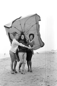 Slecht weer in het weekend. Dames met parasol maken strandwandeling, Bestanddeelnr 915-3396