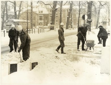 Sneeuwruimen door de Gemeentelijke Reinigingsdienst op de Kleine Houtweg bij de ingang van de Mariastichting ziende naar het Noorden. NL-HlmNHA 54011640