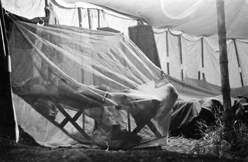 Soldaat ligt onder een klamboeng in een tent, Bestanddeelnr 456-2-4