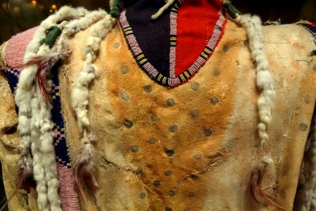 Shirt, Siksika, late 1800s, view 2, traditionally tanned hide, earth paint, glass beads, weasel (ermine) tails, feathers, wool - Glenbow Museum - DSC00998