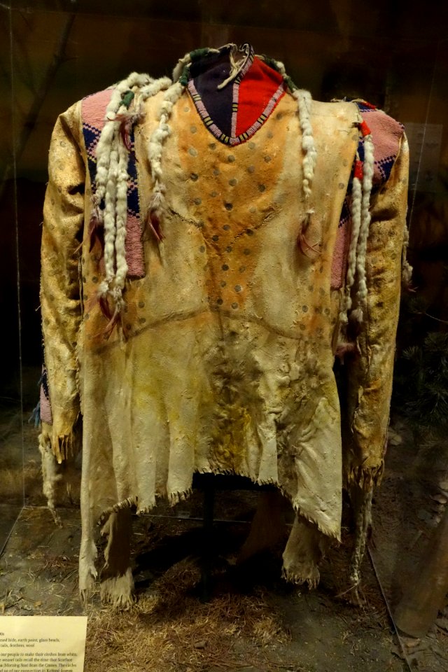 Shirt, Siksika, late 1800s, view 1, traditionally tanned hide, earth paint, glass beads, weasel (ermine) tails, feathers, wool - Glenbow Museum - DSC00993